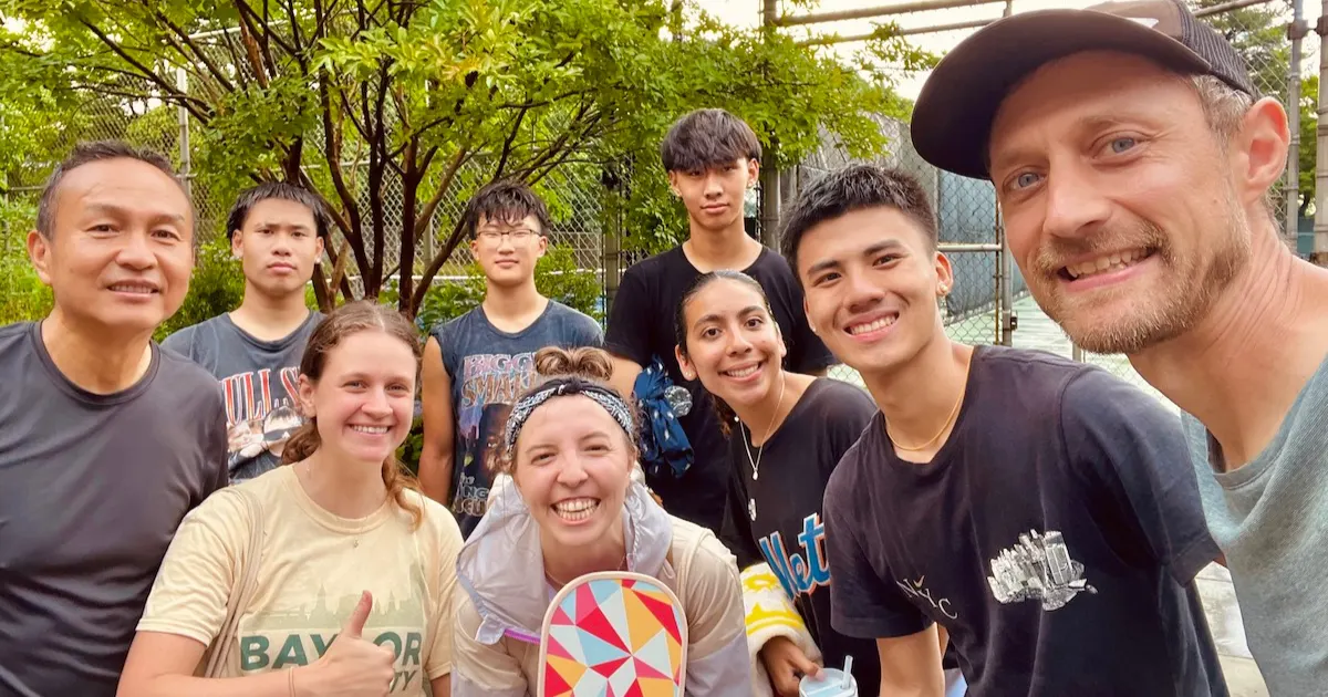 A group of about ten people smiling together outdoors after a lab — most of the people pictured are not yet following Jesus, met through ordinary relationships.